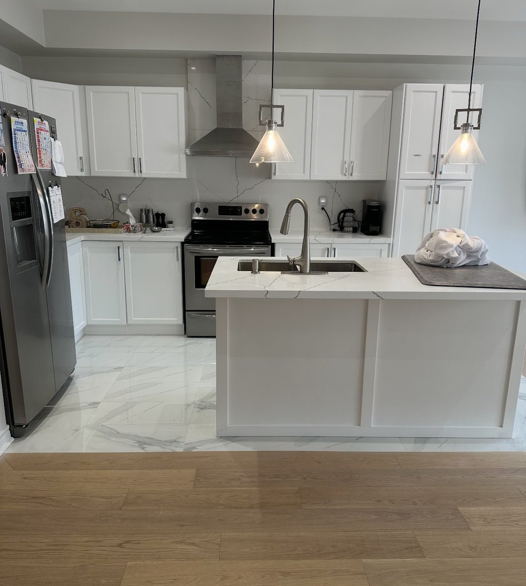 Kitchen with white cabinets, stainless appliances and dark island