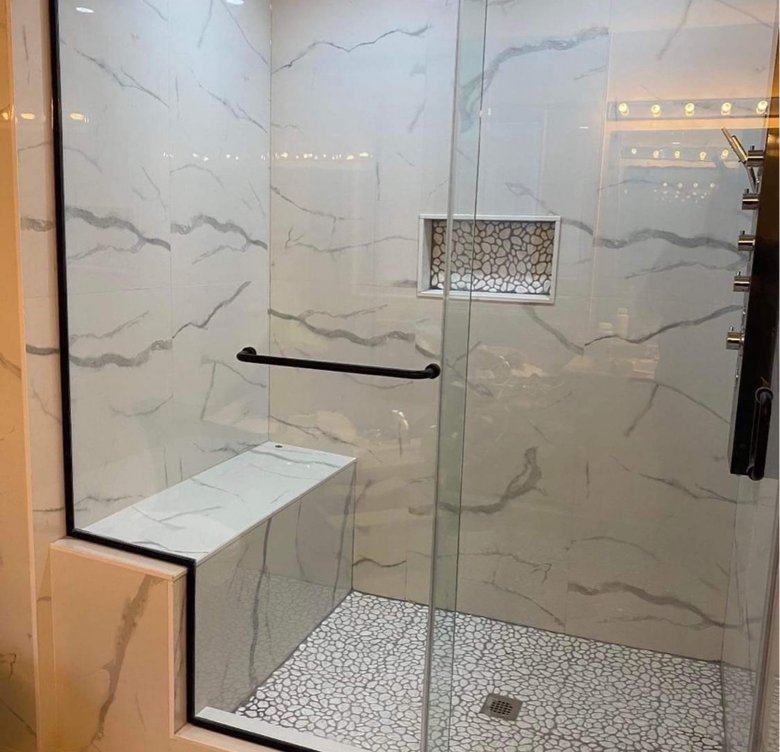 Luxurious marble-pattern shower with bench and lit niche